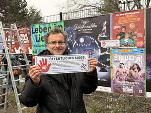 Eine Demonstrierender mit einem selbstgefertigten Siegel für das SEZ. 