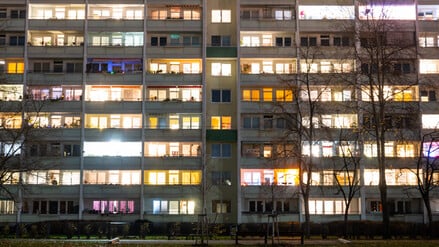 In einem Hochhaus in Lichtenberg sind einige Fenster beleuchtet. Die Zahl der Sozialwohnungen in Berlin sinkt.