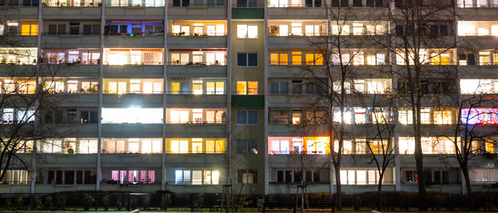 In einem Hochhaus in Lichtenberg sind einige Fenster beleuchtet. Die Zahl der Sozialwohnungen in Berlin sinkt.
