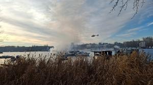 Ein Hubschrauber fliegt über dem brennenden Boot auf der Spree.