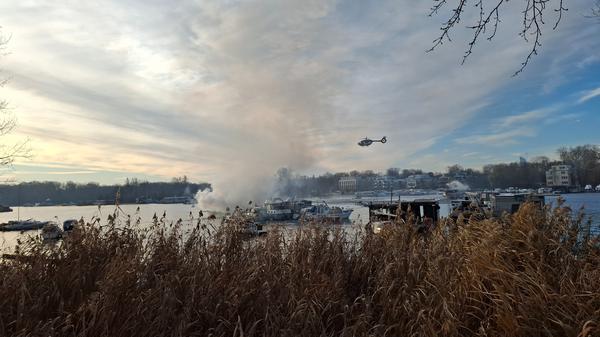 Ein Hubschrauber fliegt über dem brennenden Boot auf der Spree.
