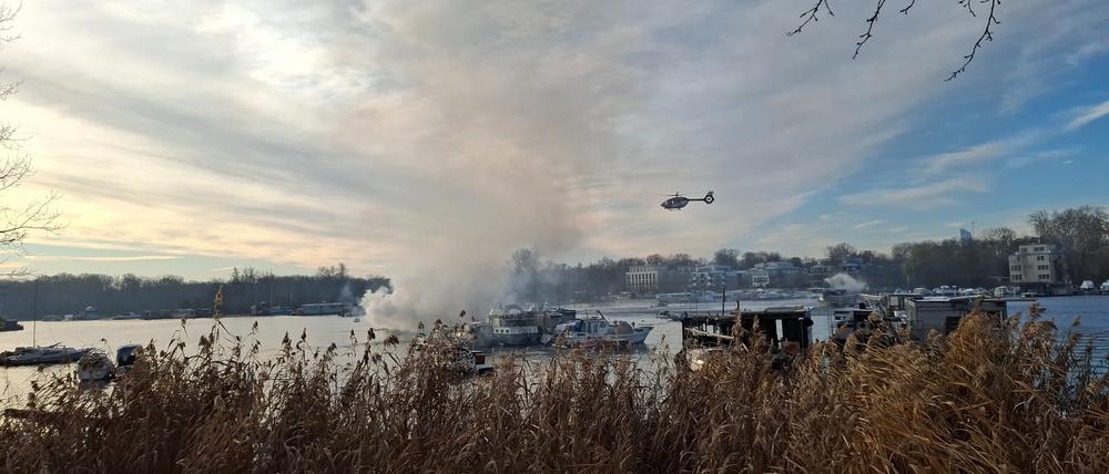 Ein Hubschrauber fliegt über dem brennenden Boot auf der Spree.