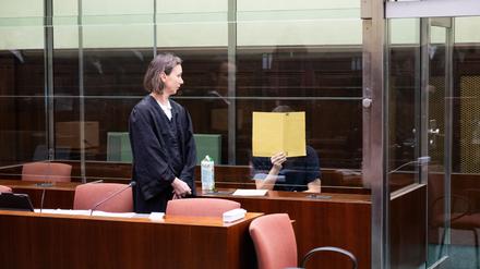 Der angeklagte mutmaßliche IS-Unterstützer sitzt zu Beginn seines Prozesses im Gerichtssaal hinter einer Glasscheibe. Davor steht seine Verteidigerin Susanne Lange.