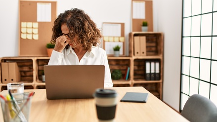Middle age hispanic woman working at the office wearing glasses tired rubbing nose and eyes feeling fatigue and headache. stress and frustration concept.