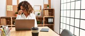Middle age hispanic woman working at the office wearing glasses tired rubbing nose and eyes feeling fatigue and headache. stress and frustration concept.