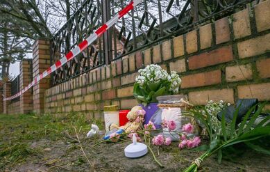 Kerzen und Blumen liegen vor einem Haus in Berlin-Mahlsdorf, in dem nach einem Feuer ein Kind gestorben ist.