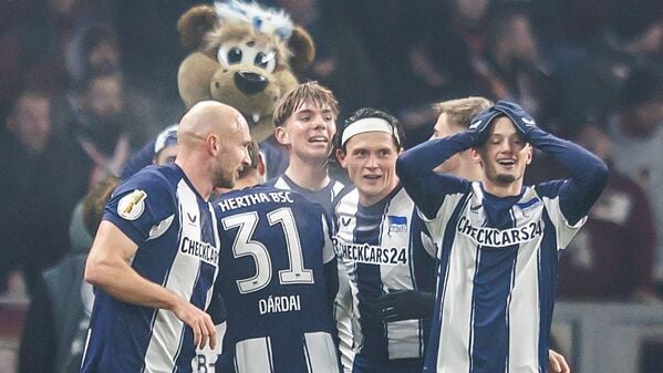 Jubelnde Hertha-Spieler mit Maskottchen.