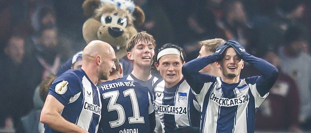Jubelnde Hertha-Spieler mit Maskottchen.
