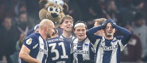 Jubelnde Hertha-Spieler mit Maskottchen.