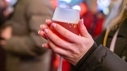 Eine junge Frau wärmt sich die Hände an einem Rosé-Glühwein.