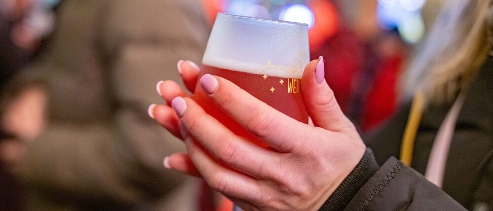 Eine junge Frau wärmt sich die Hände an einem Rosé-Glühwein.