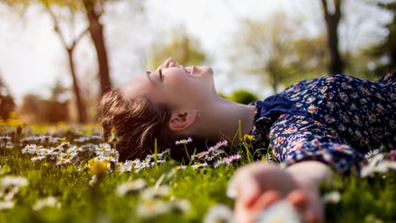 Ein junge Frau liegt entspannt auf der Wiese (Symbolbild).