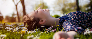 Ein junge Frau liegt entspannt auf der Wiese (Symbolbild).