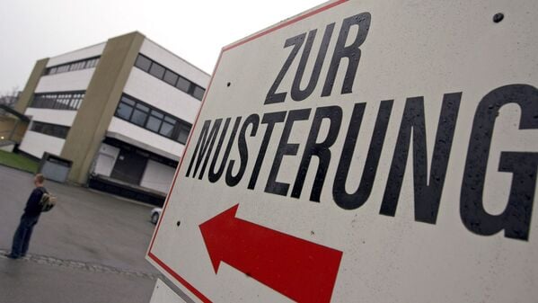 Ein Wehrpflichtiger steht unter einem Hinweisschild mit der Aufschrift „Zur Musterung“ vor dem Kreiswehrersatzamt in Kempten (Schwaben). (Symbolbild)