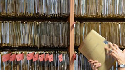 Deutsche Gegenwart: Eine Mitarbeiterin einer Behörde greift an einem Regal nach einer Akte. 