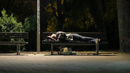 Ein Obdachloser hat sich zum Schlafen auf eine Bank gelegt (Symbolbild).