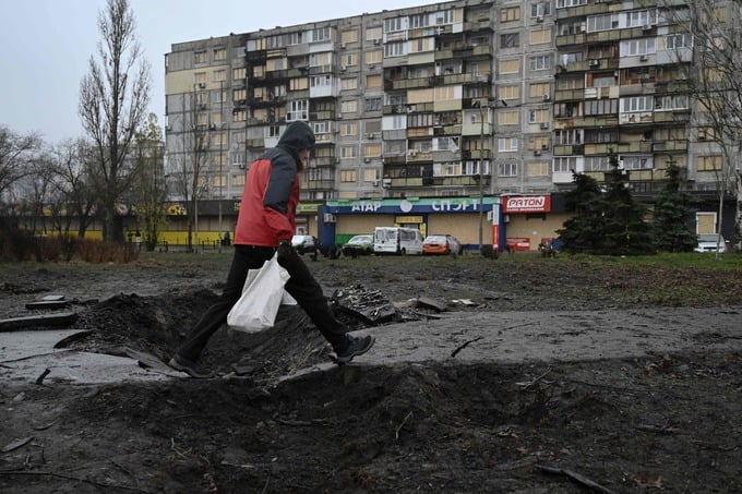 A man walks over a crater in front of a residential building damaged after a recent air attack, in Kyiv on December 3, 2025, amid the Russian invasion of Ukraine. (Photo by Genya SAVILOV / AFP)