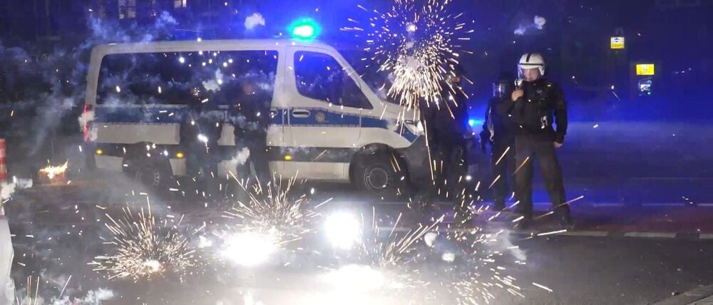 Polizeibeamte stehen am Silvesterabend hinter explodierendem Feuerwerk.