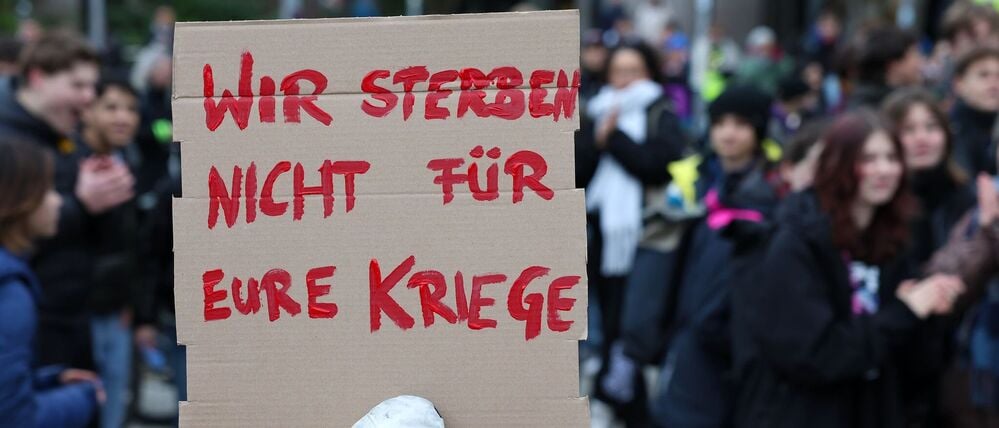 Eine Teilnehmerin hält eine Botschaft in die Kamera.