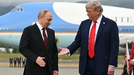 US-Präsident Donald Trump (rechts) streckt seine Hand aus, um dem russischen Präsidenten Wladimir Putin die Hand zu schütteln, während sie nach ihrer Ankunft auf der Joint Base Elmendorf-Richardson in Anchorage, Alaska, am 15. August 2025 auf einem Podium auf dem Rollfeld posieren. 