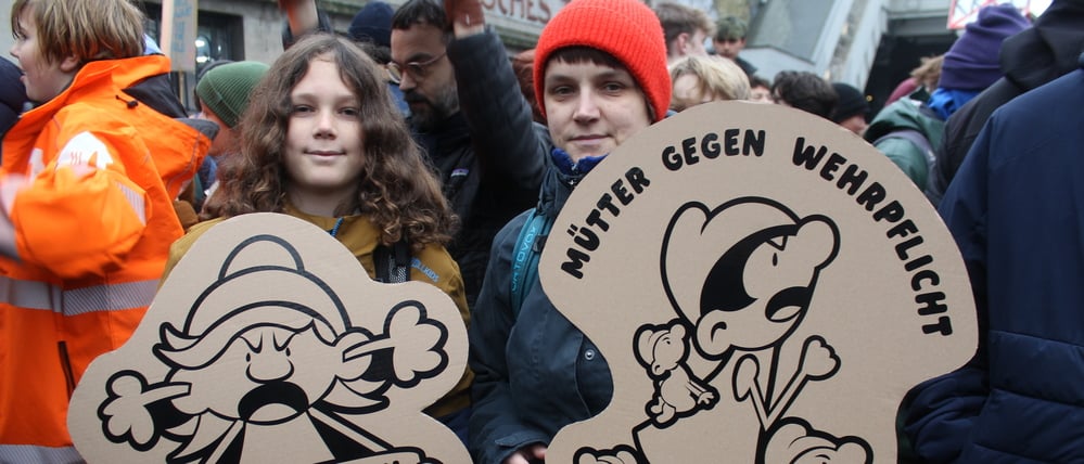 Zwei Jugendliche halten Plakate beim Schulstreik gegen die Wehrpflicht in den Händen.
