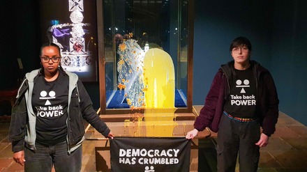 Das Bild zeigt Anhänger der zivilen Widerstandsgruppe „Take Back Power“ mit einem Banner mit der Aufschrift „Democracy has crumbled – Tax The Rich” (Die Demokratie ist zusammengebrochen – Besteuert die Reichen). 