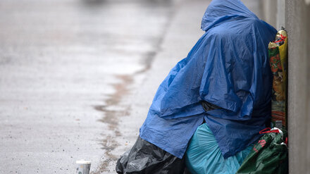 ARCHIV - 23.03.2018, Brandenburg, Potsdam: Ein Bettler sitzt mit einem Regenumhang am Rande eines Gehweges. (zu dpa: ´Weniger Straftaten gegen Obdachlose in Brandenburg») Foto: Ralf Hirschberger/dpa +++ dpa-Bildfunk +++