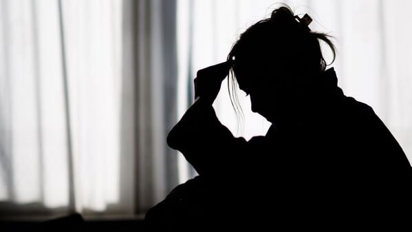 Silhouette einer Frau vor einer hellen Fensterfront