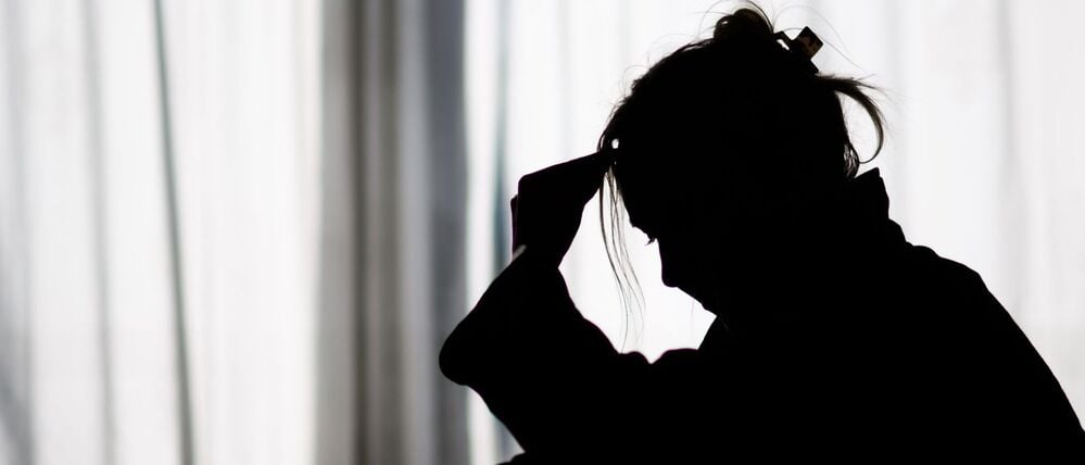 Silhouette einer Frau vor einer hellen Fensterfront