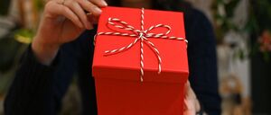 Eine Frau öffnet eine mit einer Schleife verzierte Geschenkbox. An Weihnachten legt sich rund ein Viertel der Bundesbürger inzwischen auch ein Geschenk für sich selbst auf den Gabentisch. 