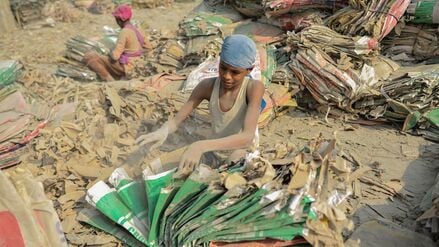 Kinder sortieren inmitten von Zementstaub gebrauchte Zementsäcke am Ufer des Surma-Flusses in Sylhet, Bangladesch.
