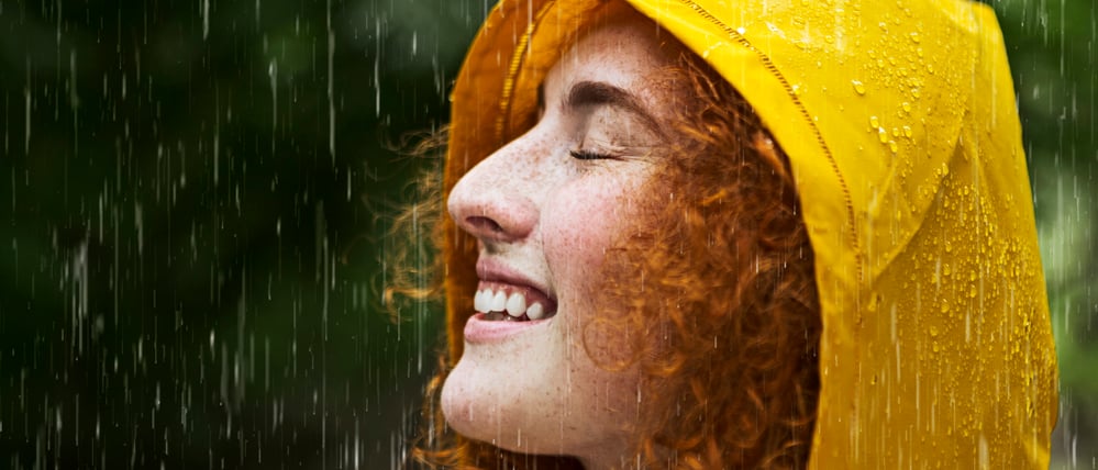 Eine fröhliche, rothaarige Frau im Regen.