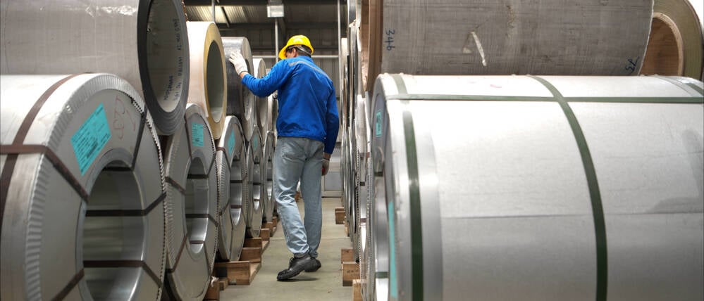 Industriearbeiter bei der Inspektion eines großen Metallrohrs in einer Fabrik (Symbolbild).