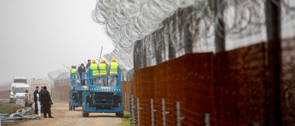 Arbeiter befestigen Stacheldraht am Zaun entlang der ungarischen Grenze zu Serbien.