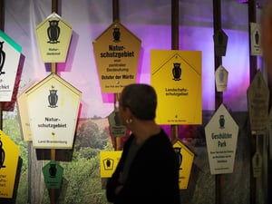 Eine Person läuft vor Schildern mit dem typischen Eulen-Symbol in der Sonderausstellung im Naturkundemuseum Potsdam.