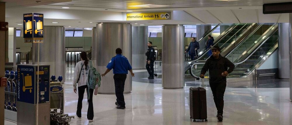 Menschen mit Koffern gehen durch das internationale Terminal des Newark Liberty International Airport.