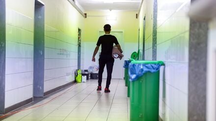 Ein Migrant geht in der Zentralen Aufnahmeeinrichtung für Asylbewerber in Bayern mit der Erstausstattung an Besteck, Bettwäsche und Hygieneartikeln über einen Gang zu seinem Wohnbereich (Symbolbild).