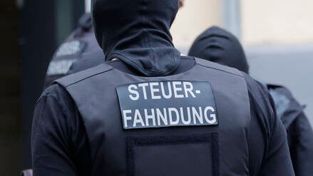 „Steuerfahndung“ steht auf der Weste eines Beamten (Symbolbild).