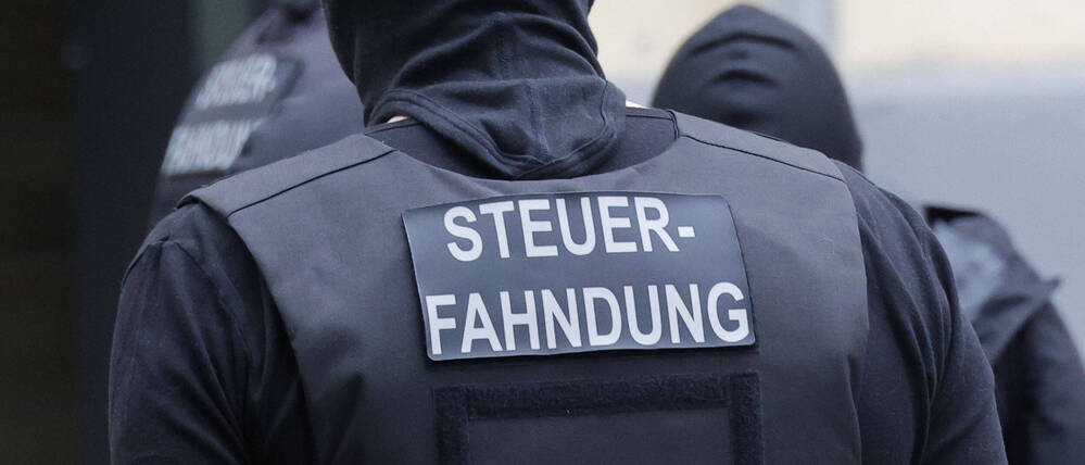 „Steuerfahndung“ steht auf der Weste eines Beamten (Symbolbild).