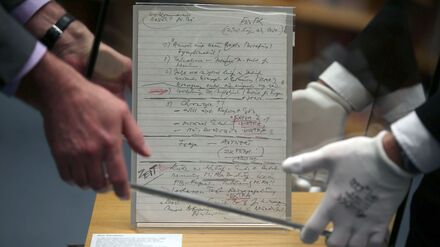 Mitarbeiter stülpen im Haus der Geschichte eine Glasvitrine über den Schabowski-Zettel. Um das Ausstellungsstück gibt es seit Jahren Streit mit einem Journalisten. (Archivbild)