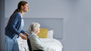 Eine Frau hilft in einer Wohnung einer Seniorin im Rollstuhl (Symbolfoto).