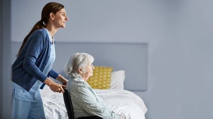 Eine Frau hilft in einer Wohnung einer Seniorin im Rollstuhl (Symbolfoto).