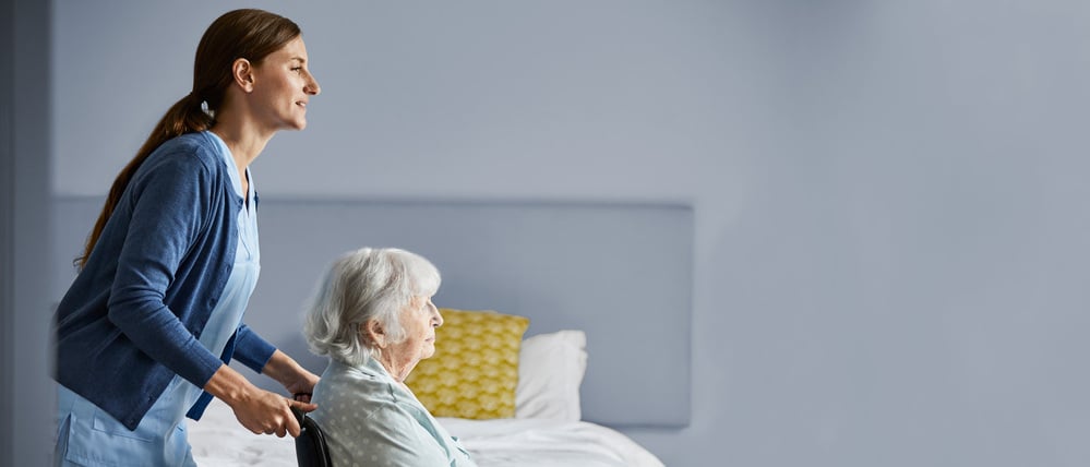 Eine Frau hilft in einer Wohnung einer Seniorin im Rollstuhl (Symbolfoto).