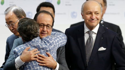 Der damalige französische Präsident François Hollande umarmt nach der Annahme des Abkommens Christiana Figueres von der Klimarahmenkonvention der Vereinten Nationen. Der damalige französische Außenminister Laurent Fabius (rechts) hatte die Verhandlungen in Paris geleitet.