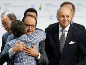 Der damalige französische Präsident François Hollande umarmt nach der Annahme des Abkommens Christiana Figueres von der Klimarahmenkonvention der Vereinten Nationen. Der damalige französische Außenminister Laurent Fabius (rechts) hatte die Verhandlungen in Paris geleitet.