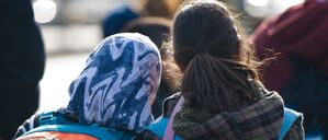 Ein Mädchen mit Kopftuch steht neben einem Mädchen ohne Kopfbeckedung.