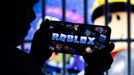 Ein Junge posiert für ein Foto, während er ein Gamepad vor einem Bildschirm hält, auf dem das Logo der US-amerikanischen Gaming-Plattform Roblox zu sehen ist. Diese Illustration stammt vom 8. Dezember 2025.
