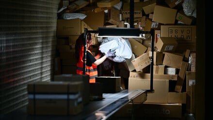 Eine Arbeiterin verlädt in der DHL-Zustellbasis Charlottenburg Pakete.