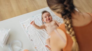 Ein Baby liegt auf einem Tuch und schaut seine Mutter an.