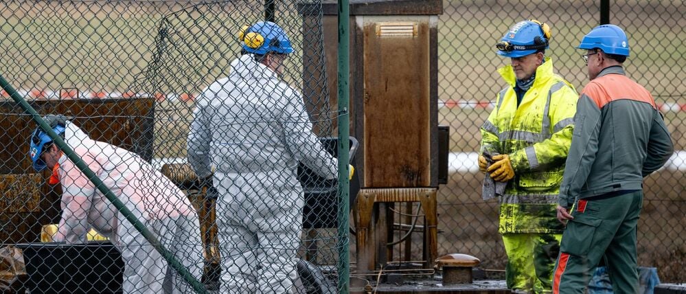 Arbeiter stehen nach einem Leck an einer PCK-Pipeline.